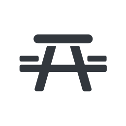 Icon of a picnic table in black on a white circular background. The table is shown from the side, with two benches on either side and angled legs.